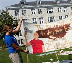 A Middlebury student hangs a banner for Sustainability Solutions Lab.