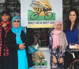 Jiran participants stand with friends in front of a bike non-profit.