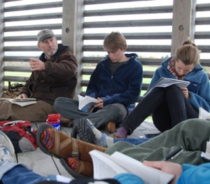 A Middlebury professor and students sit and study at the Knoll.