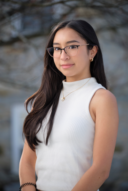 Photo of Roxy Alvarado wearing glasses, a white turtle neck, and gold jewelry. 