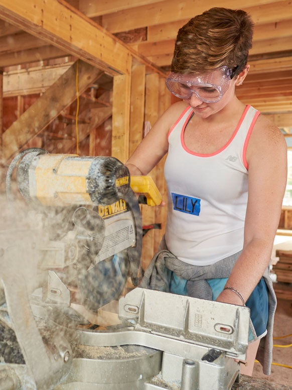A student works a saw at a local Habitat for Humanity house.