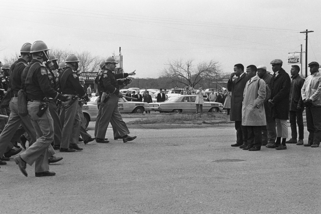 a black and white photo of police approaching civil rights protestors on the Edmund Pettus bridge