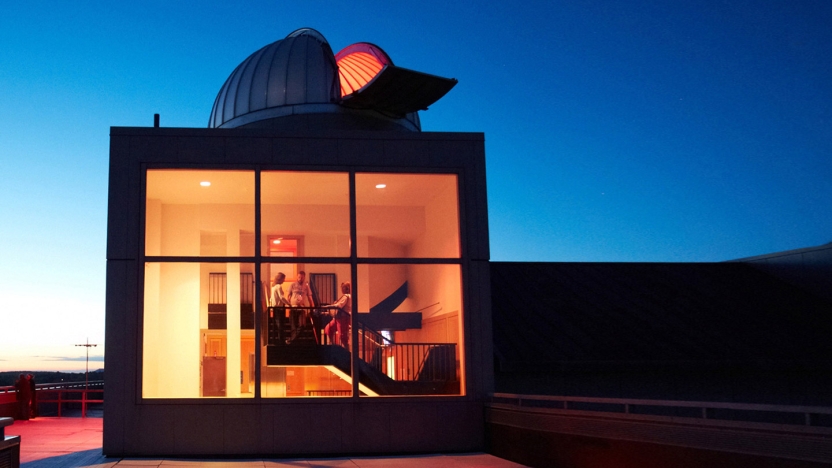 Nighttime view of Middlebury's Mittelman Observatory lit up from inside.