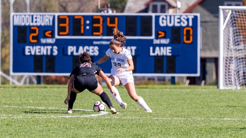 A close up of two women playing in a varsity soccer game on the Middlebury field. 