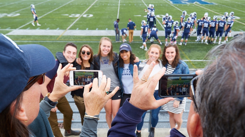 Students pose for a family photo during a fall football game.