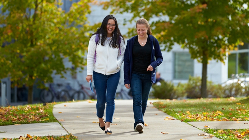 Two students walk across the main quad in early fall.