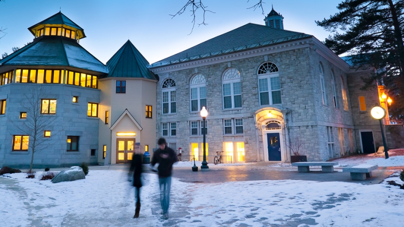 Two students catch up outside McCullough Student Center at dusk in early winter.