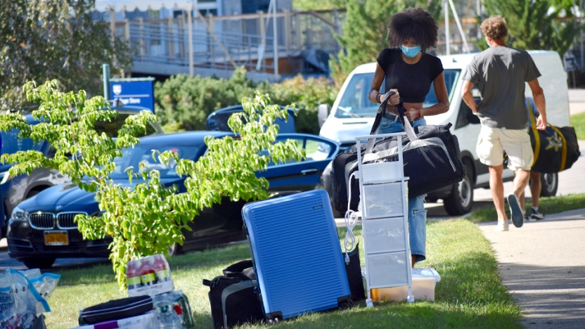 Student with suitcases outside on move in day.
