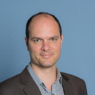 Man in shirt and coat smiling