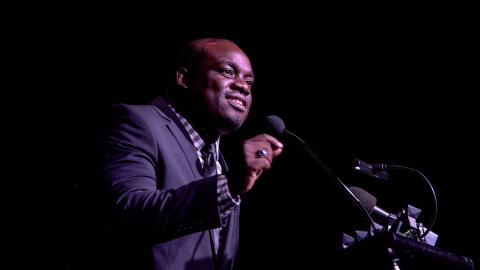 Man gesturing while speaking into a microphone