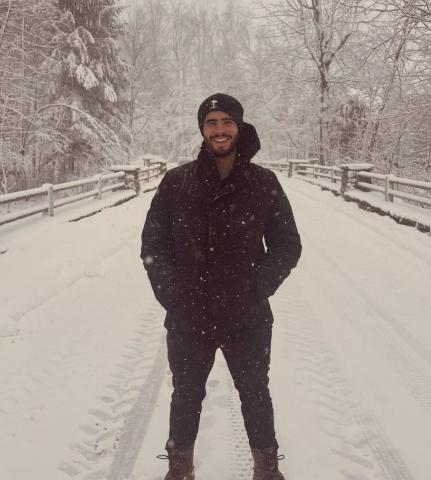 Person dressed in black standing on a snow covered bridge