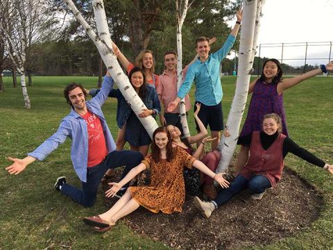 People outside leaning on a tree