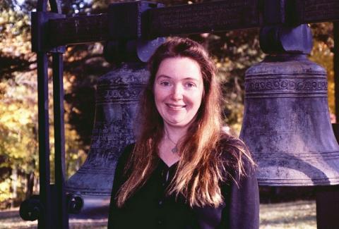 Amy Heebner standing outdoors in front of two large bells