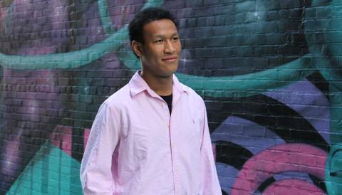 Person in pink shirt standing in front of a wall