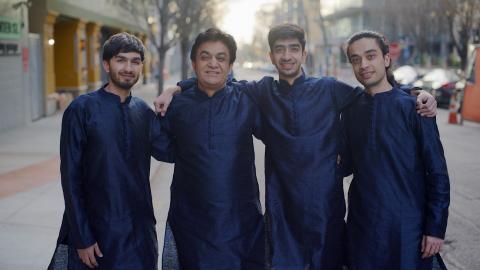 4 people standing next to each other dressed in blue