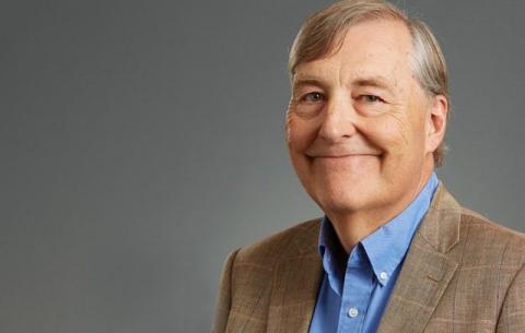 Man wearing a blue shirt and tie and brown coat.