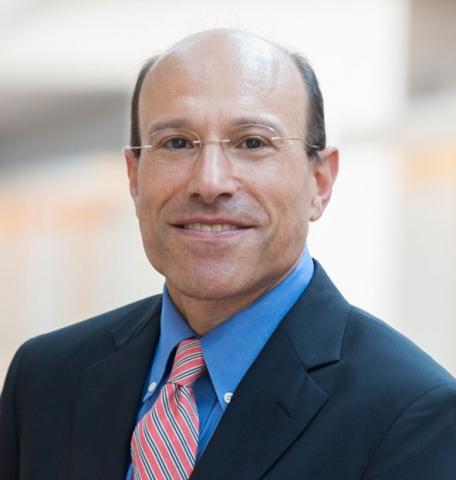Image of a man wearing a blue shirt and coat and a pink tie.