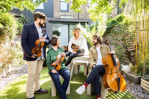 The Castalian Quartet sitting outside with their instruments