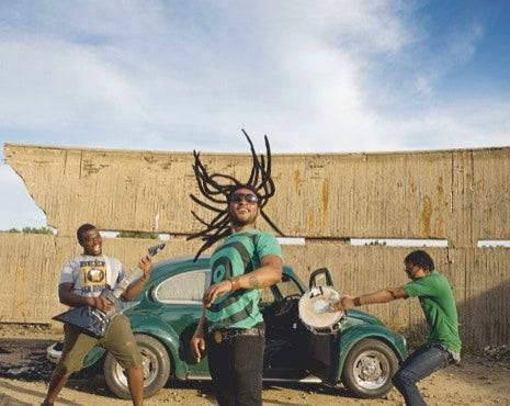 3 people standing in front of a VW Bug playing instruments