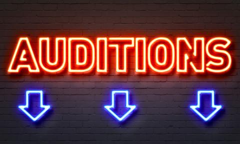 Black brick wall with the word "Auditions" in neon caps with three arrows pointing down