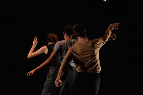 three dancers seen from behind on a black background