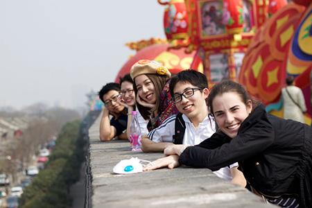 Photograph of 5 people leaning over a stone wall