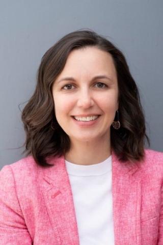 Woman with dark hair wearing a pink blazer