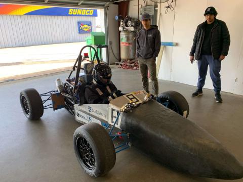 Hybrid race car, with the Middlebury logo and college students