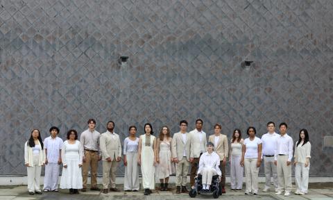 people dressed in white standing in a line in front of a gray wall
