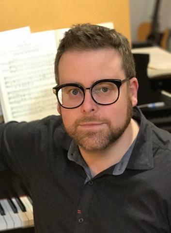 The composer sitting at a piano