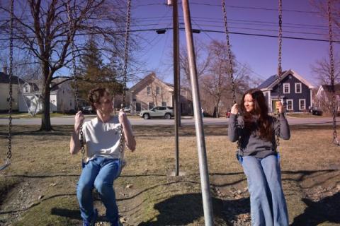 Two sitting people on playground swings