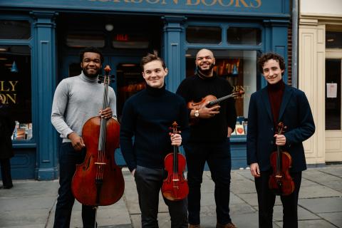 members of the quartet standing outside holding their instruments
