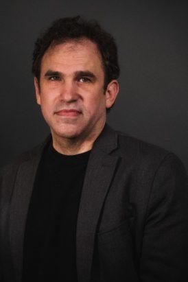 Robert Mickey in dark suit looking at the camera.