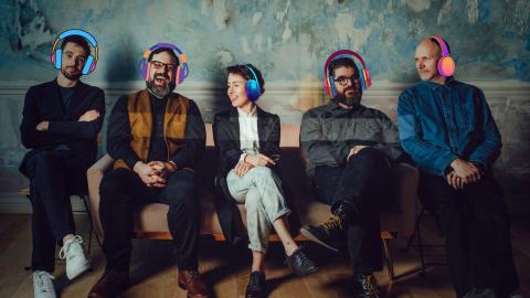 five seated people wearing headphones