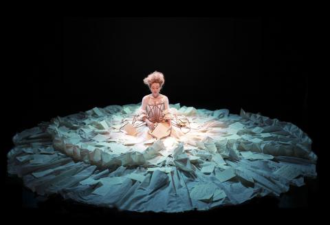 actor in the spotlight sitting on a dark stage