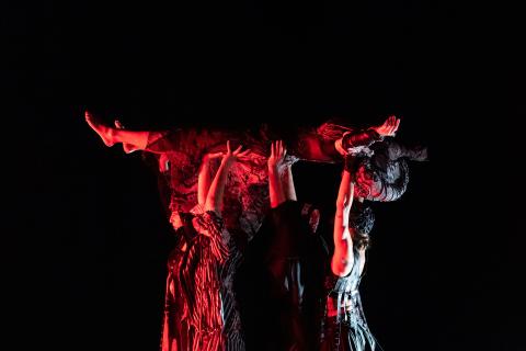 people dancing under a red light with a black background