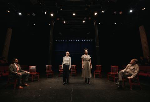 four actors on stage, two standing and two seated