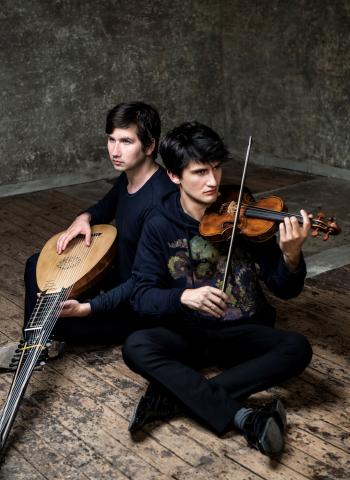 two artists sitting on the floor holding their instruments