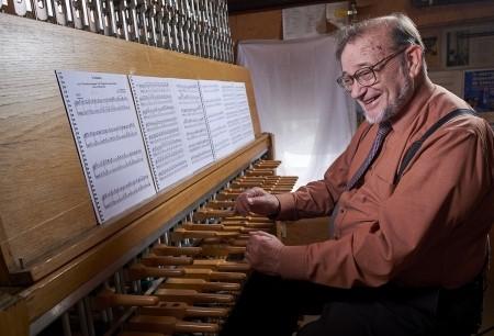 Man sits in front of music scores at the carillon instrument.