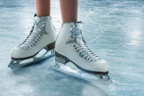A person is wearing a pair of ice skates on a surface of ice.