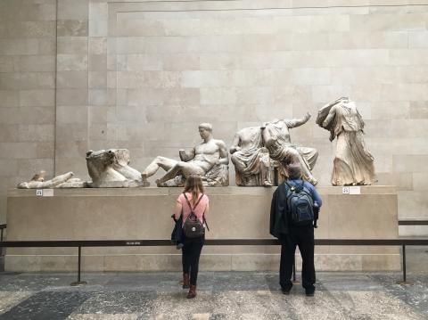 Two people look at a series of classical sculptures