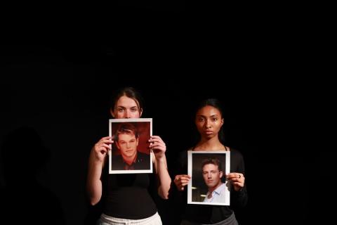 Before a black background two young woman hold a photograph facing the viewer. One photo is of Matt Damon and the other is of Ben Affleck.