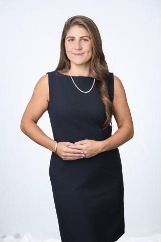 Anoush Baghdassarian stands in a black dress with hands folded.