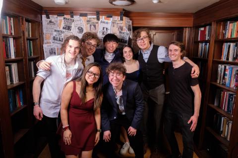 A group of people in formal wear standing in front of book shelves.