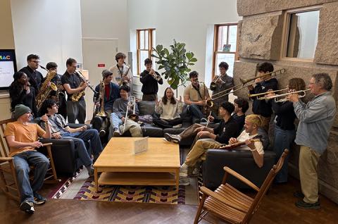 members of the ensemble sitting around a coffee table with their instruments