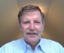 Man with a mustache wearing a blue and white striped shirt