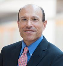Image of a man wearing a blue shirt and coat and a pink tie.