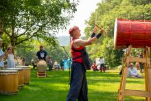 Taiko drummer standing at large, elevated drum