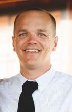 Image of a man wearing a dark colored tie and white shirt