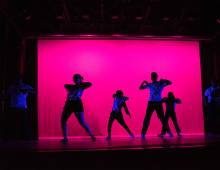 Dancers in blacklight against a pink background